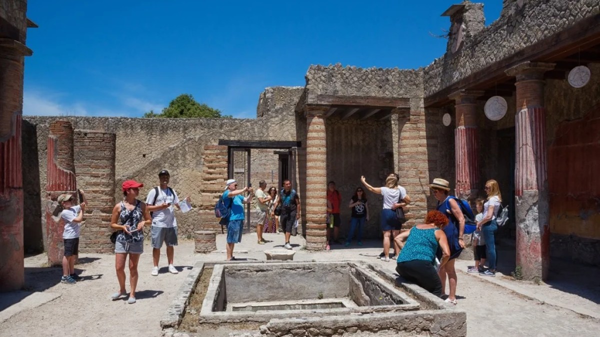 a group of people walking in front of a stone building