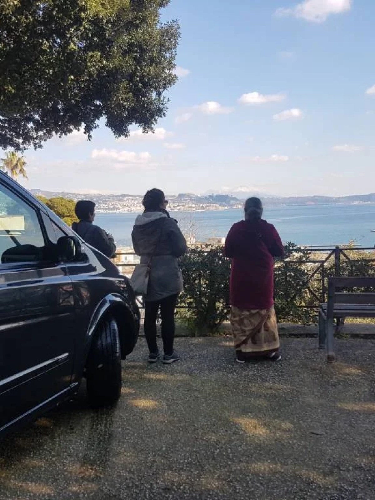 a person sitting on a bench in front of a car