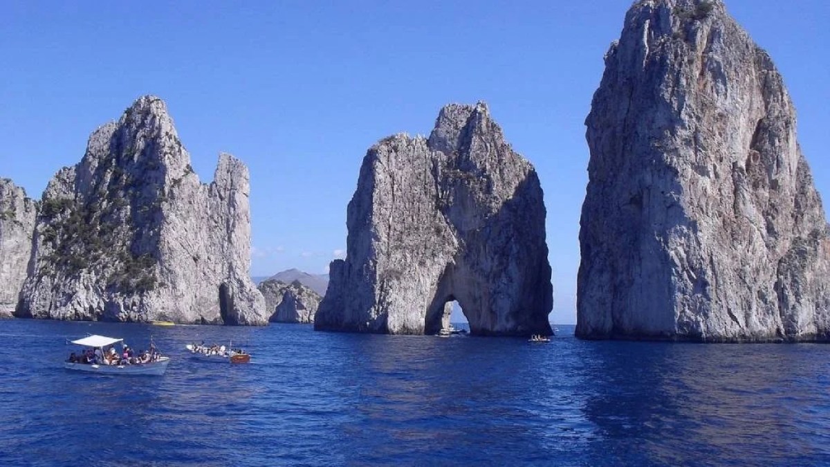a large body of water with Faraglioni in the background
