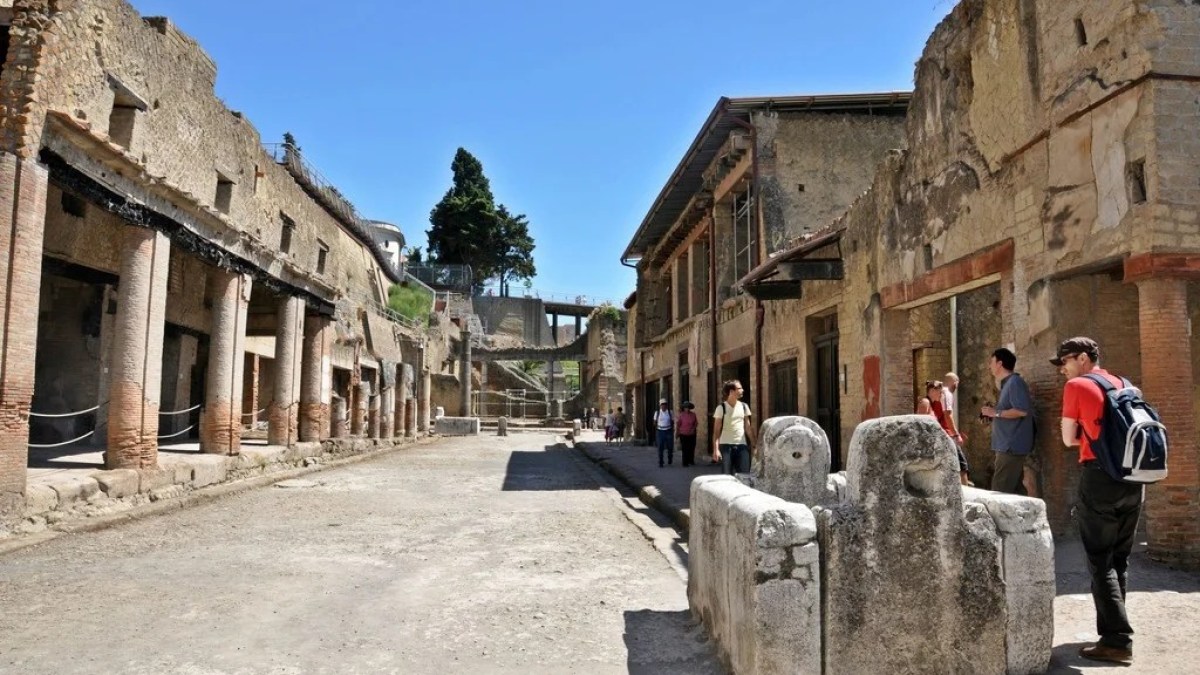 a group of people walking in front of a stone building