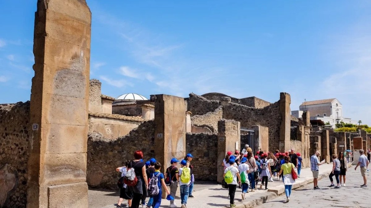 a group of people walking in front of a stone building