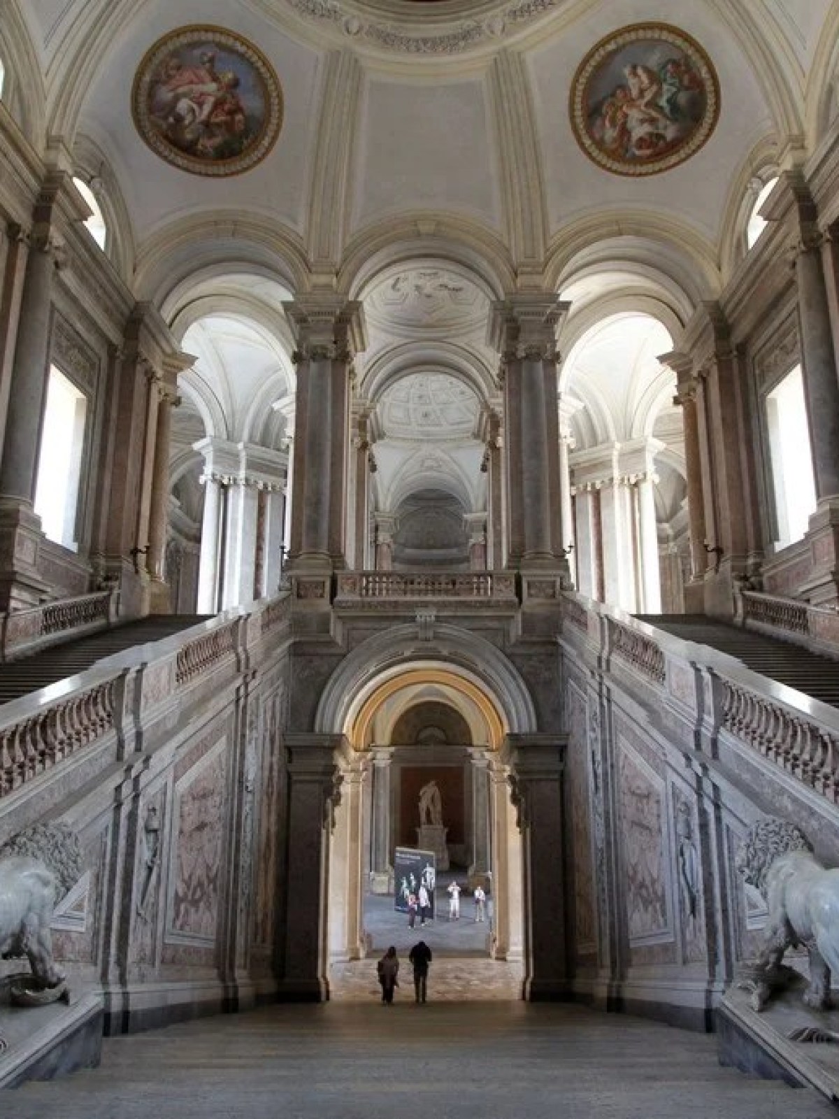 a statue of a church with Palace of Caserta in the background