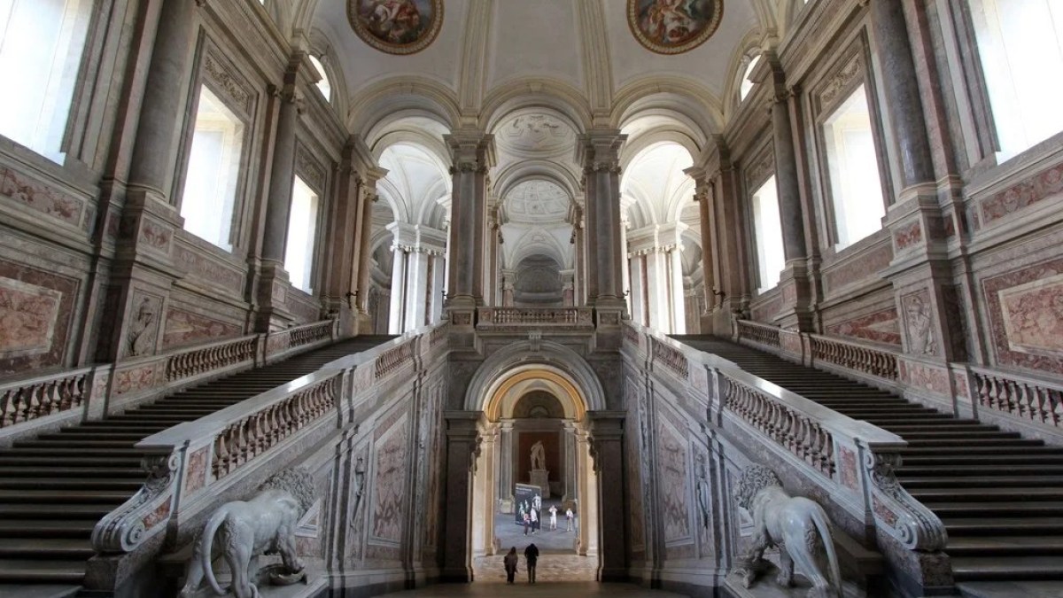 a statue of a church with Palace of Caserta in the background