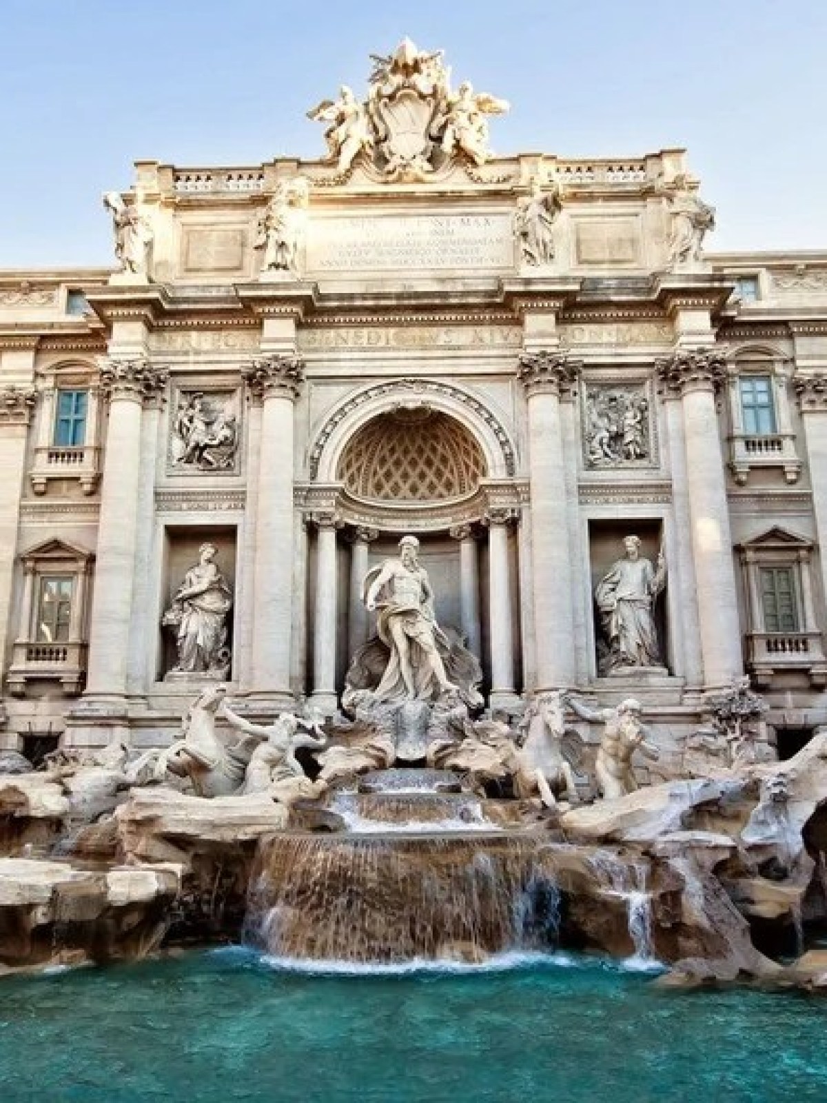 a large brick building with many windows with Trevi Fountain in the background