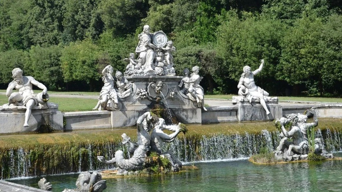 a flock of birds sitting on a bench in a park with Linderhof Palace in the background