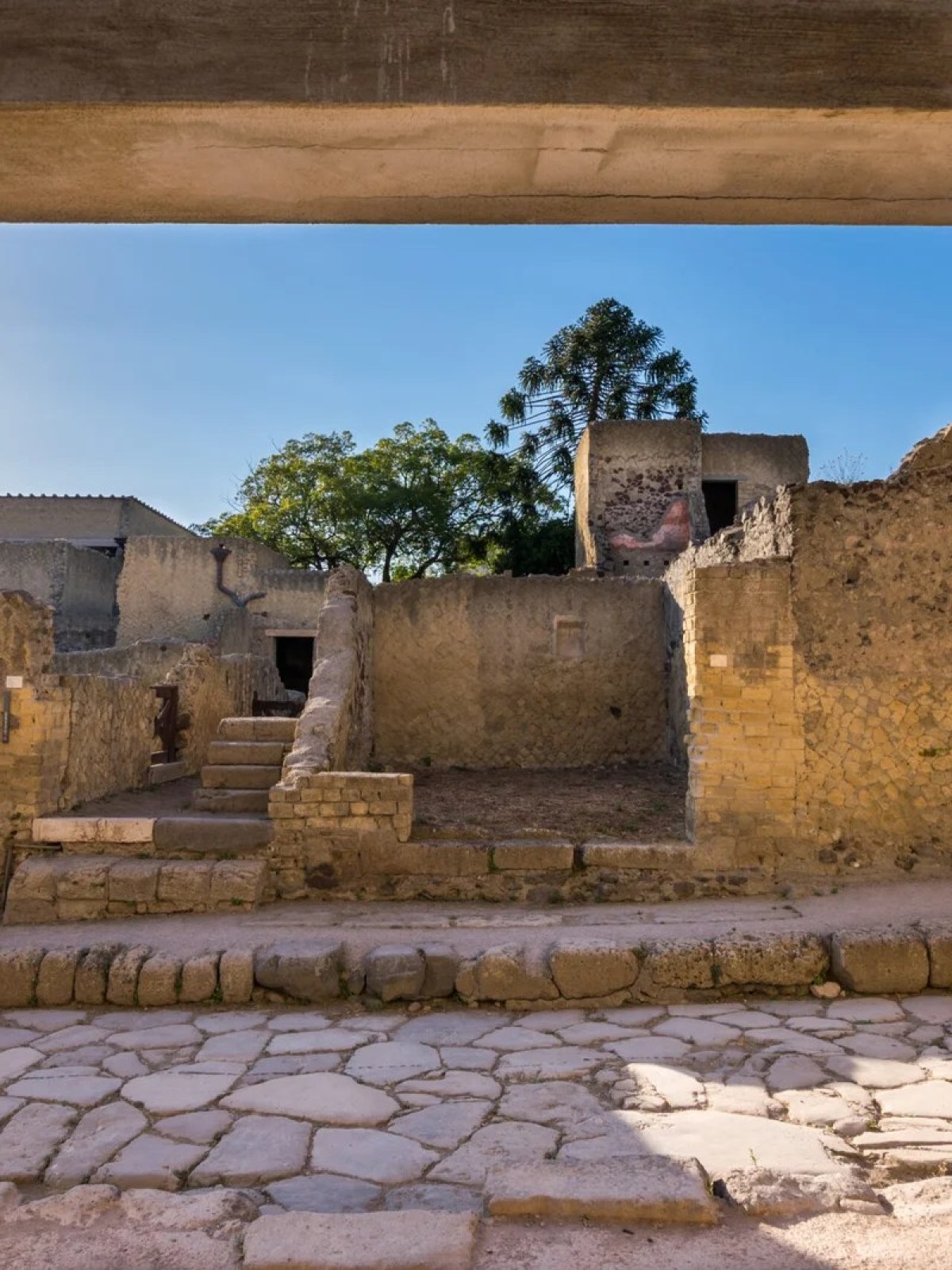 a stone building that has a bench in front of a brick wall