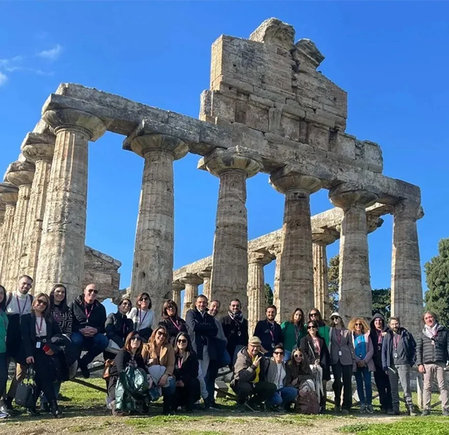 img_aboutus_2 a group of people standing in front of a stone building