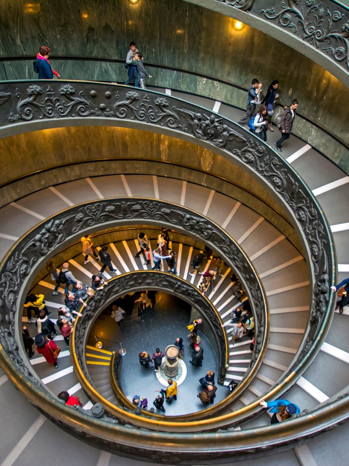 a clock that is on a metal object with Vatican Museums in the background