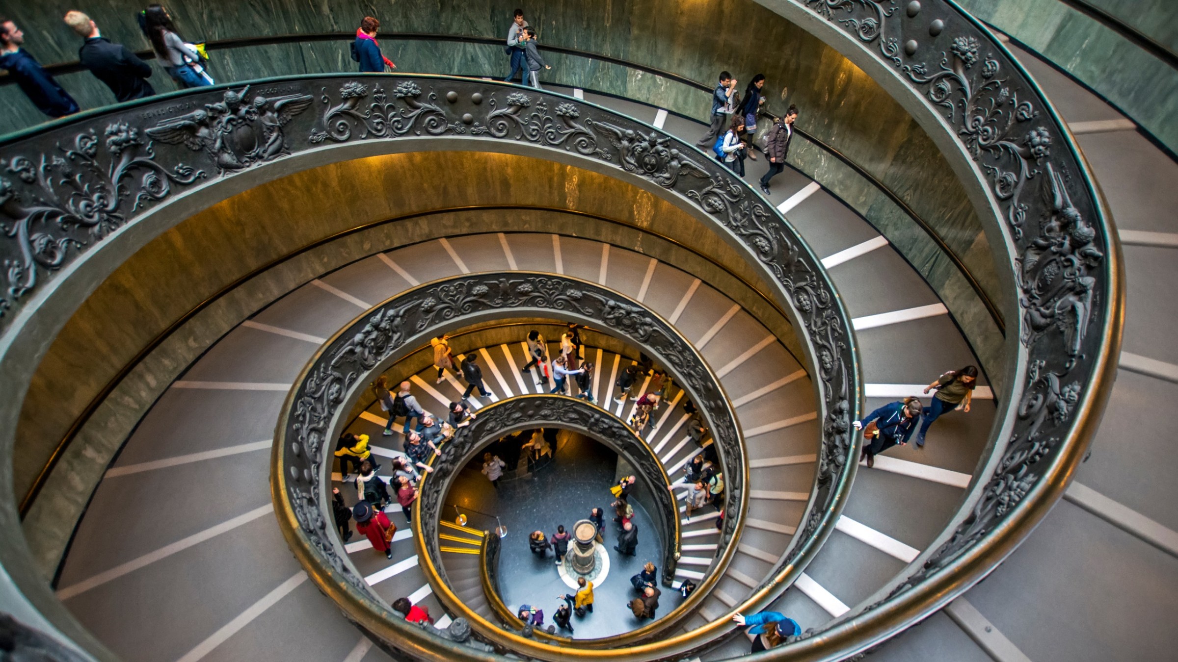 a clock that is on a metal object with Vatican Museums in the background