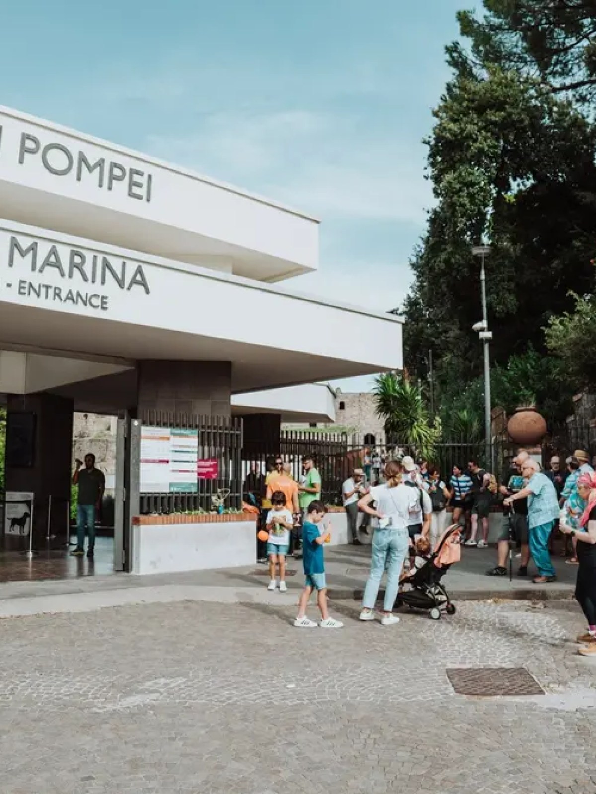 Entrance to Pompeii ruins with a crowd of people waiting outside.
