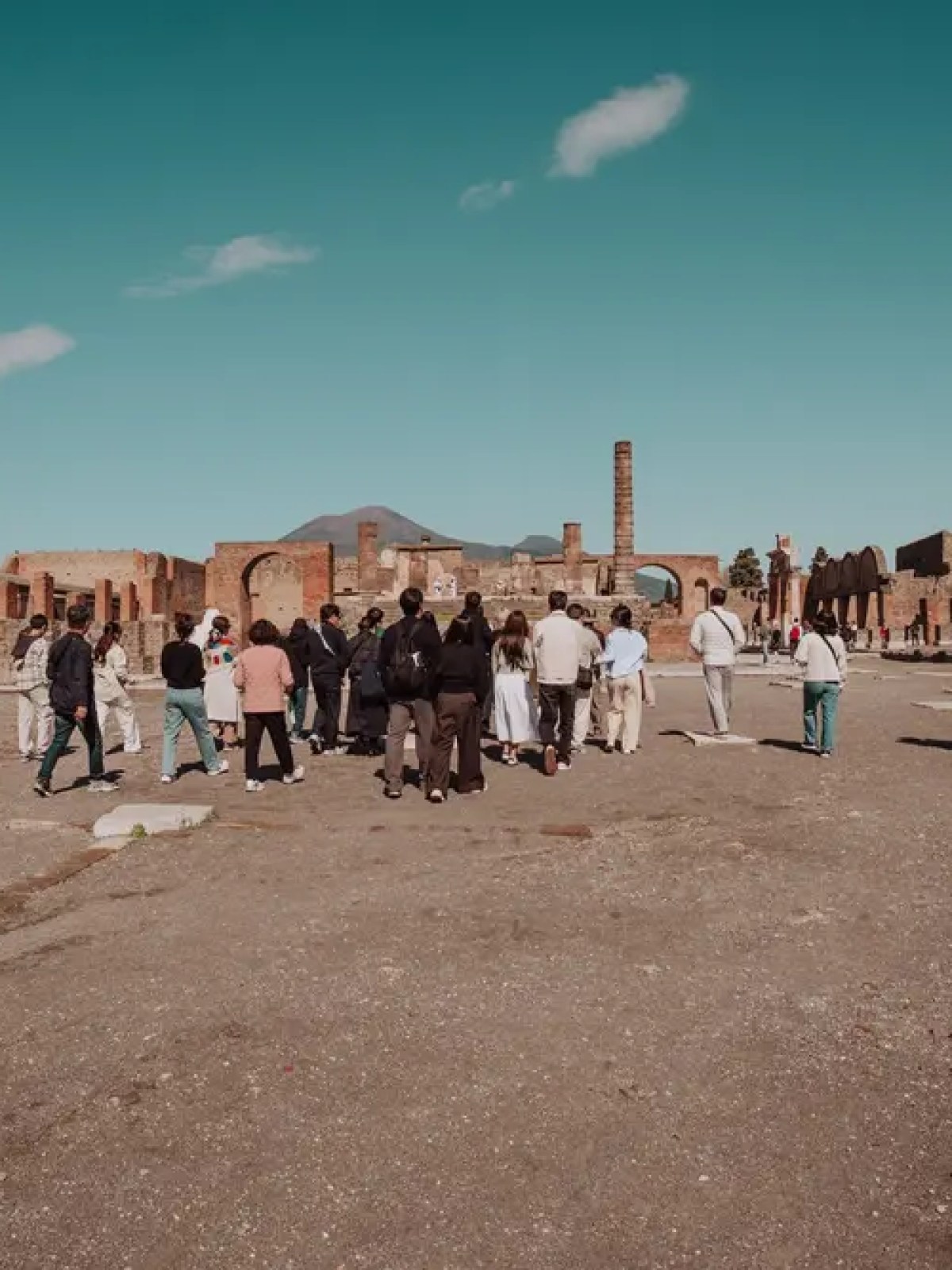 A group of people exploring ancient ruins under a clear blue sky.