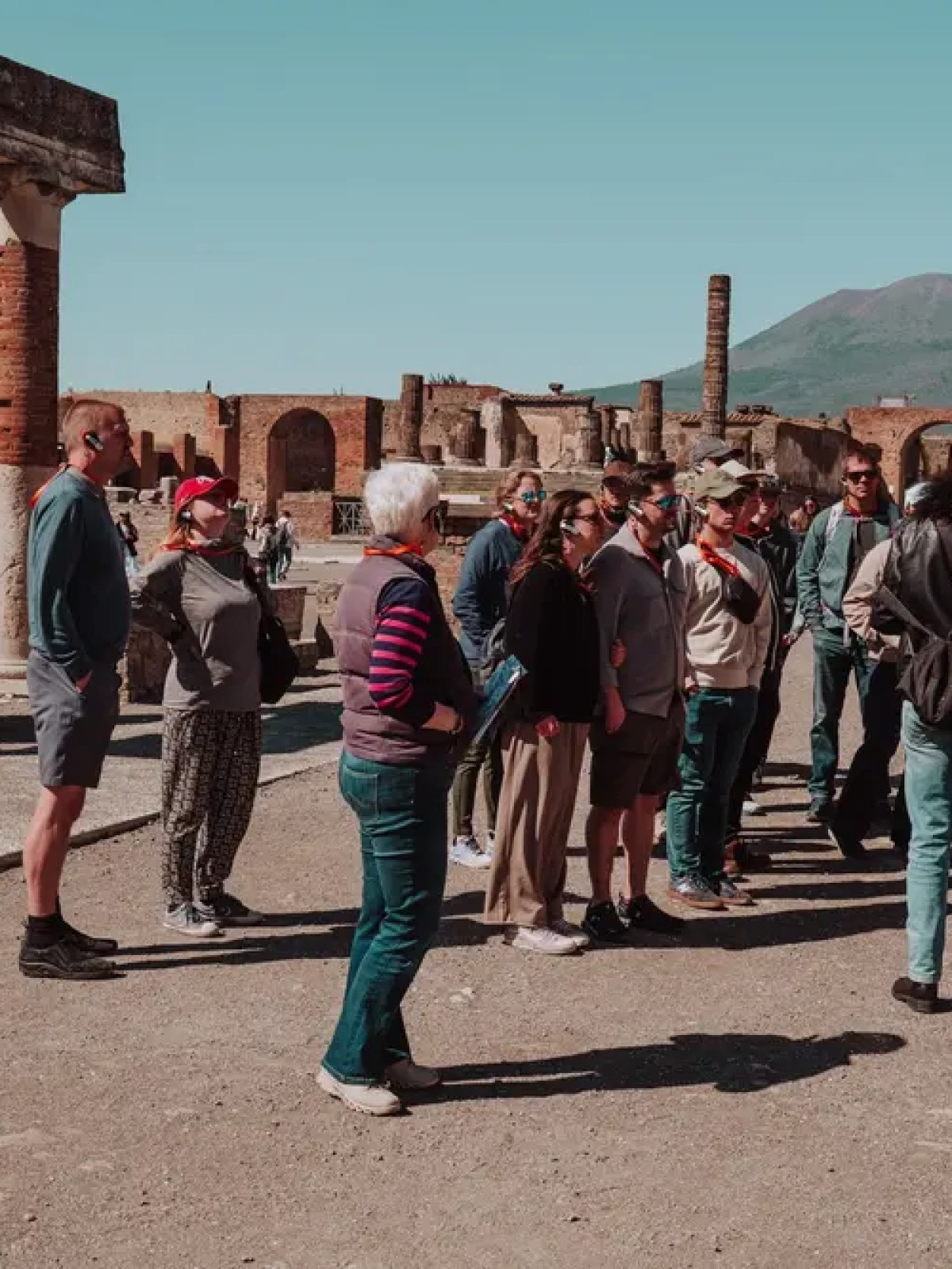 Tour group at an ancient ruins site with a mountain in the background.