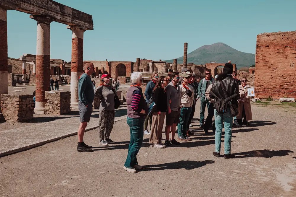 Tour group at an ancient ruins site with a mountain in the background.
