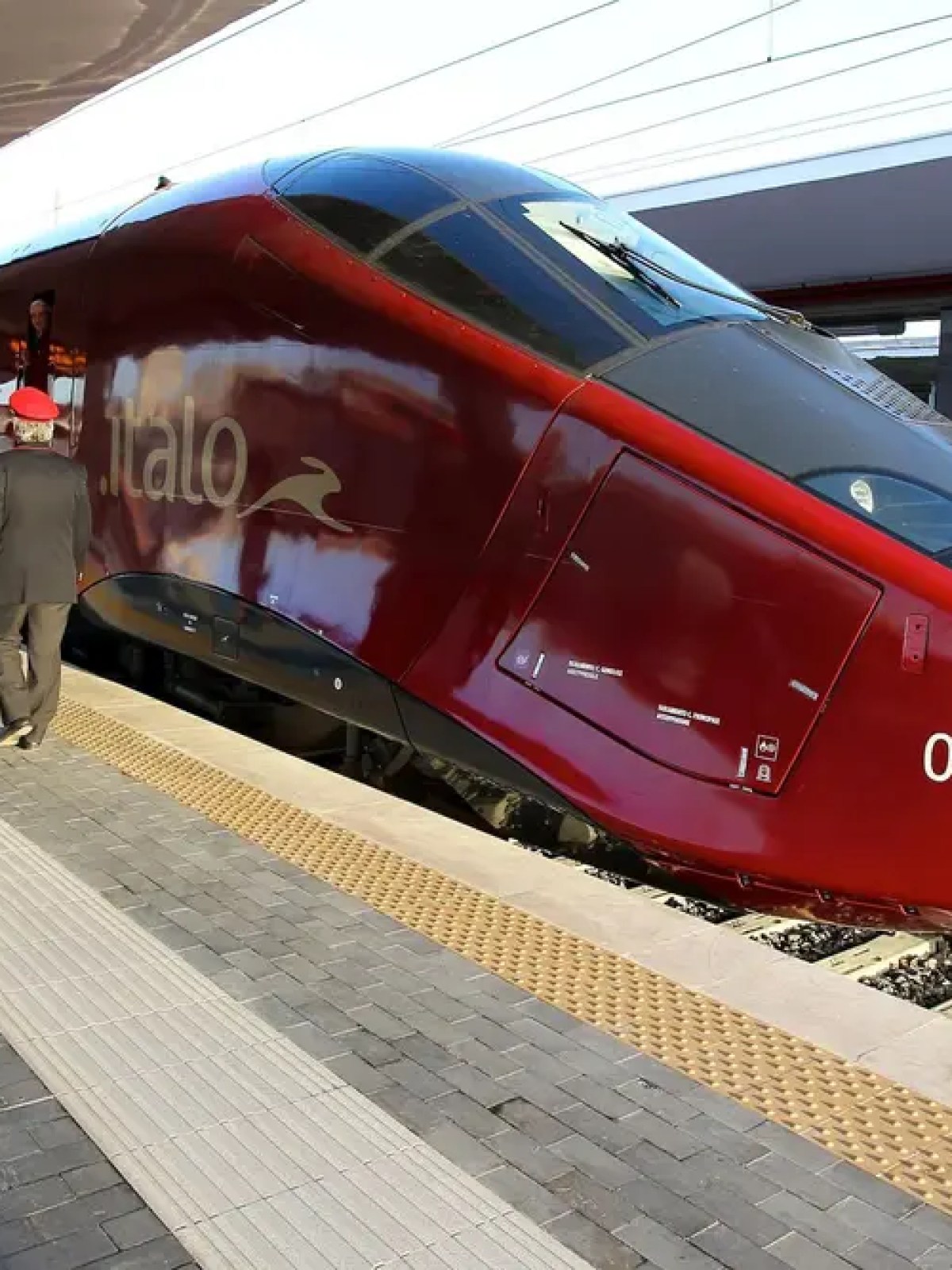 Red high-speed train at a platform with passengers boarding.