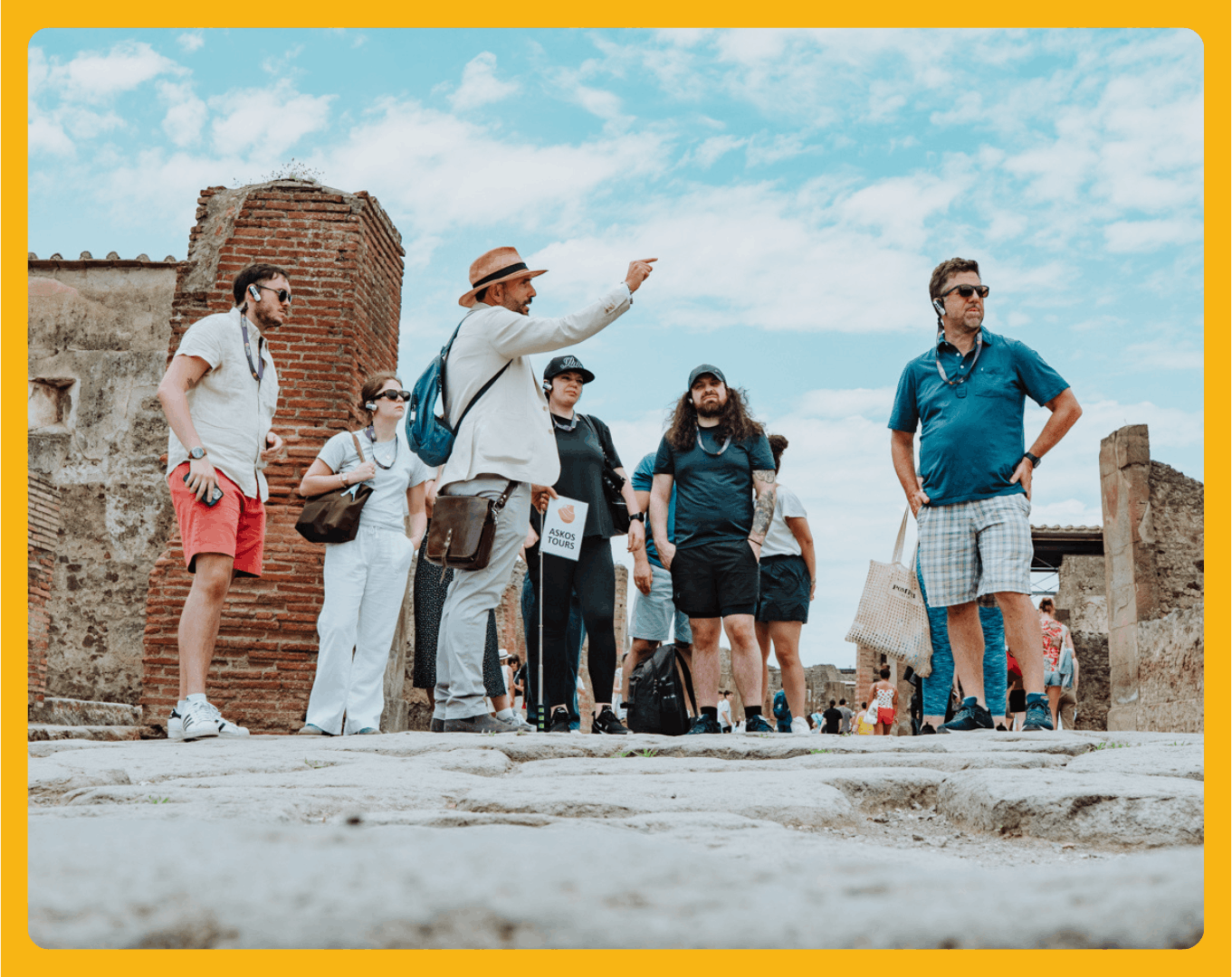 Group of tourists with a guide in ancient ruins, under a blue sky.
